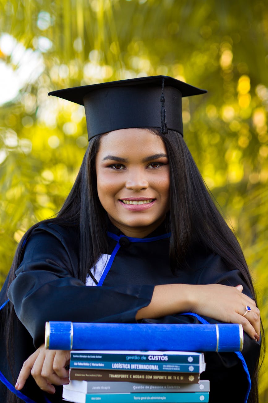 happy young ethnic student in graduation cap with textbooks