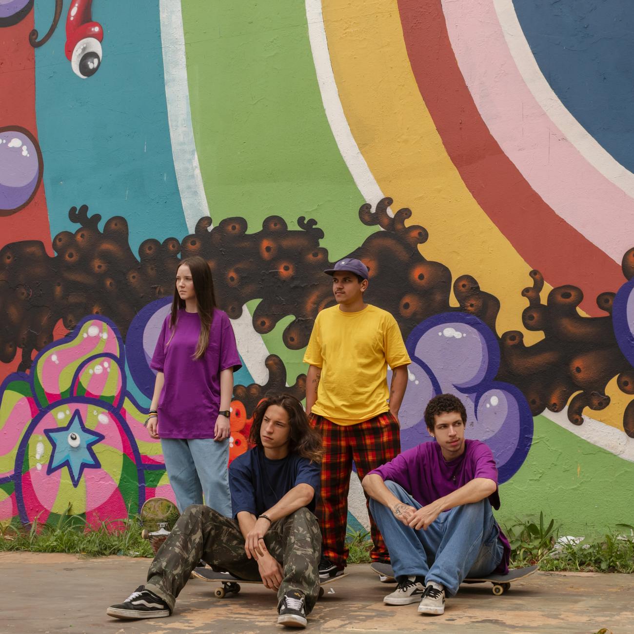 people sitting on skateboard and standing near mural painting